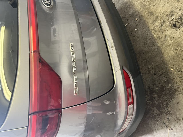 Gray rear hatch dent around the Sportage badge