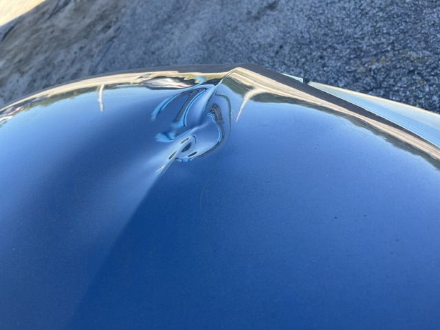 Dark hood with a visible dent near the front edge