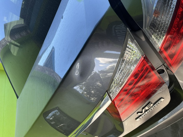 Gray trunk panel with a dent beside the taillight